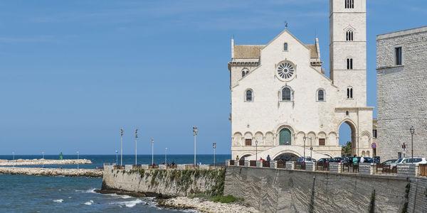 View of building by sea against blue sky