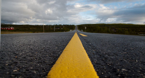 Surface level of road against cloudy sky