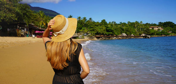 Female tourist with sundress and straw hat on ilhabela island, sao sebastiao, brazil