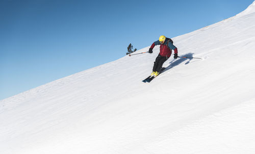 Mature man skiing on mountain slope against sky