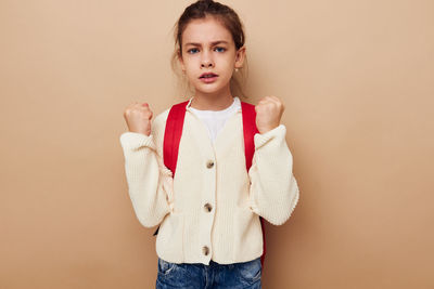 Portrait of young woman standing against pink background