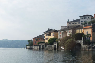 Houses by river in town against sky