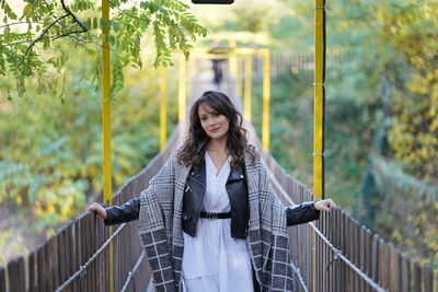 Portrait of young woman standing against railing