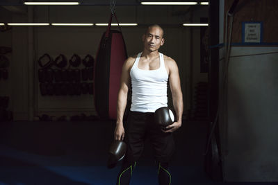Portrait of sportsman holding boxing gloves standing in gym