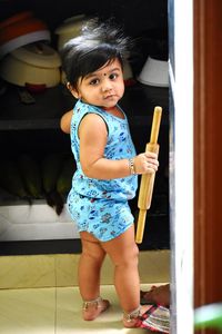 Full length portrait of cute baby girl holding rolling pin at home