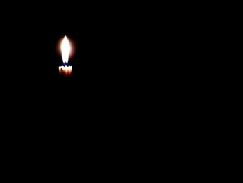 Close-up of lit candle in dark room