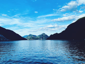 Scenic view of sea and mountains against blue sky