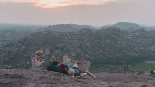 People sitting on mountain against sky