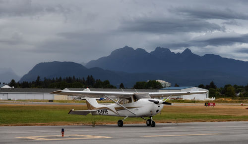 Airplane at airport runway against sky