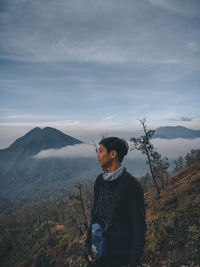Young man looking at mountains against sky