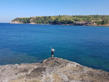 Woman standing on rock against sea