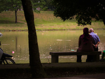 Rear view of man sitting at riverbank