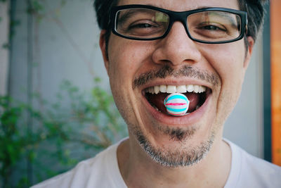 Close-up portrait of young man wearing eyeglasses having candy in his mouth