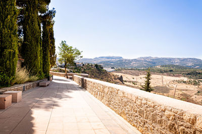 Footpath leading towards mountains against clear sky