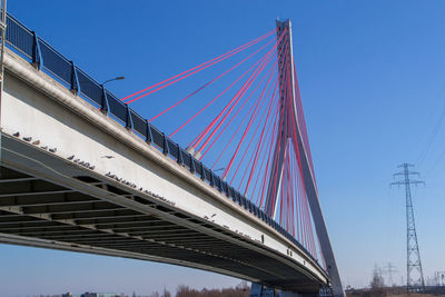 Low angle view of suspension bridge against clear blue sky