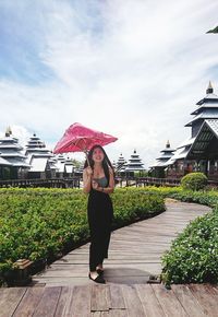 Full length of woman standing on boardwalk against sky