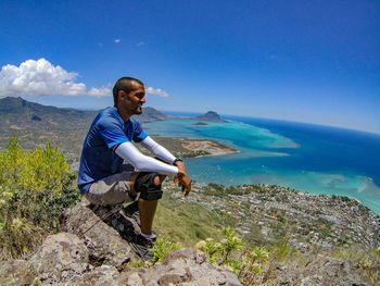 Man sitting on rock at beach