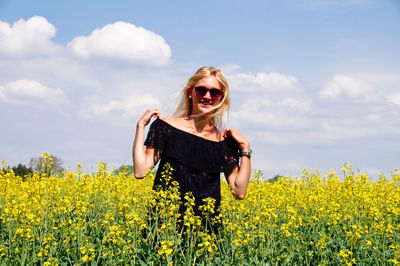 Portrait of smiling young woman standing on oilseed rape field