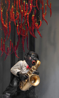 Red chili peppers hanging over figurine with saxophone