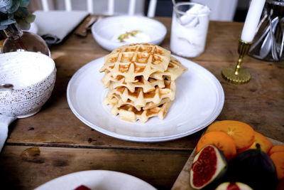 High angle close-up of waffles stacked in plate on wooden table