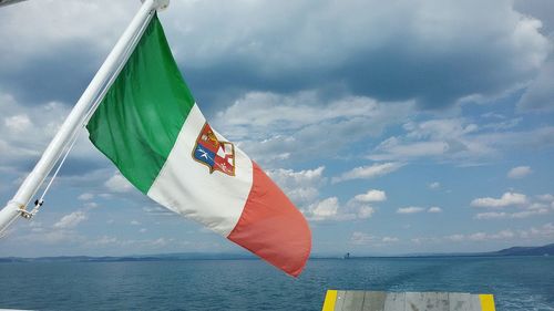 Scenic view of flag on sea against sky
