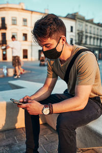 Young man using mobile phone in city