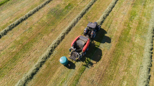 Black tractor with a red straw chamber press during the straw harvest on a mown field