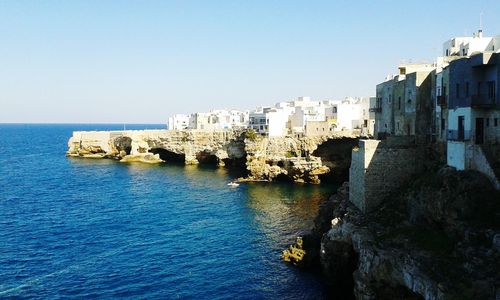 View of town by sea against clear blue sky