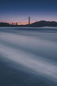 Golden gate bridge over sea against clear sky during sunset