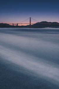 View of suspension bridge in city at sunset