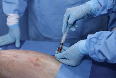 Midsection of doctor performing surgery on patient