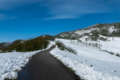 Road amidst snowcapped mountains against sky