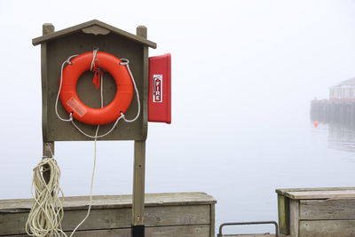 Red life preserver on pier by river against foggy back ground.