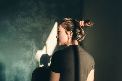 Rear view of woman standing against wall