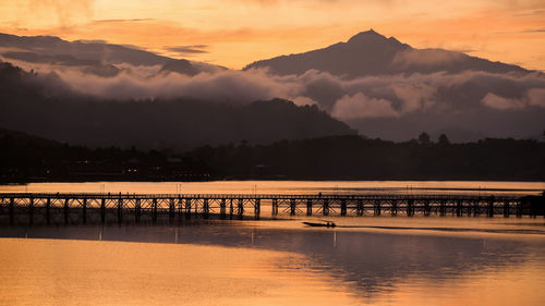 Pier over lake against sky during sunset