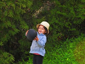 Cute girl holding balloon while standing against plants