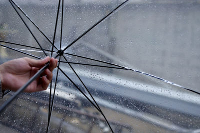 Cropped hand holding umbrella during rainfall