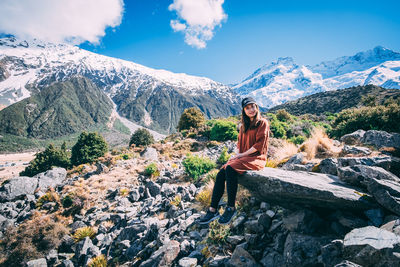 Woman sitting on rock against mountains