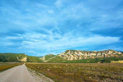 Scenic view of road by mountains against sky