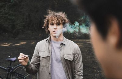 Portrait of young man smoking cigarette at roadside