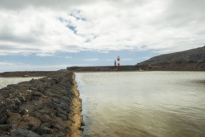 Lighthouse by sea against sky