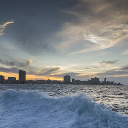 Scenic view of sea and buildings against sky during sunset