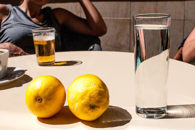 Drinks and oranges on table against woman sitting in background