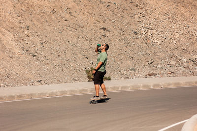 A man playing figure skating on a rural road in the sun on a bright day, play surf skate