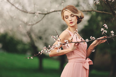 Woman holding branch while standing outdoors