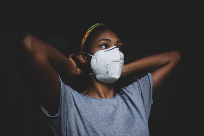 Young woman putting face mask on before going out