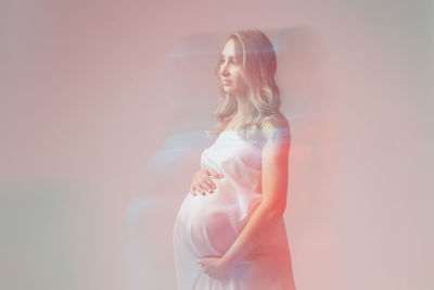 Side view of young woman standing against wall
