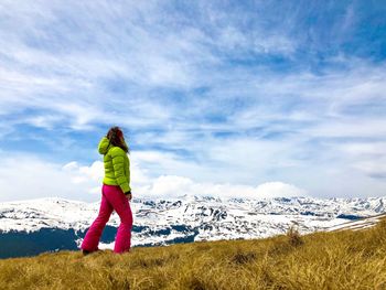 Rear view of person standing on snowcapped mountain against sky