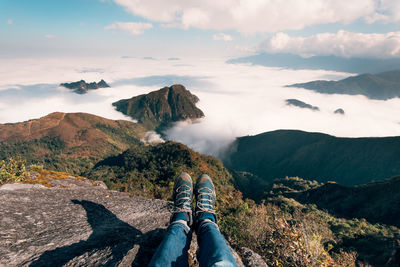 Low section of person on mountain against sky