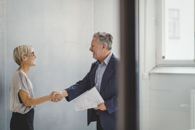 Mature businessman and businesswoman shaking hands in new office